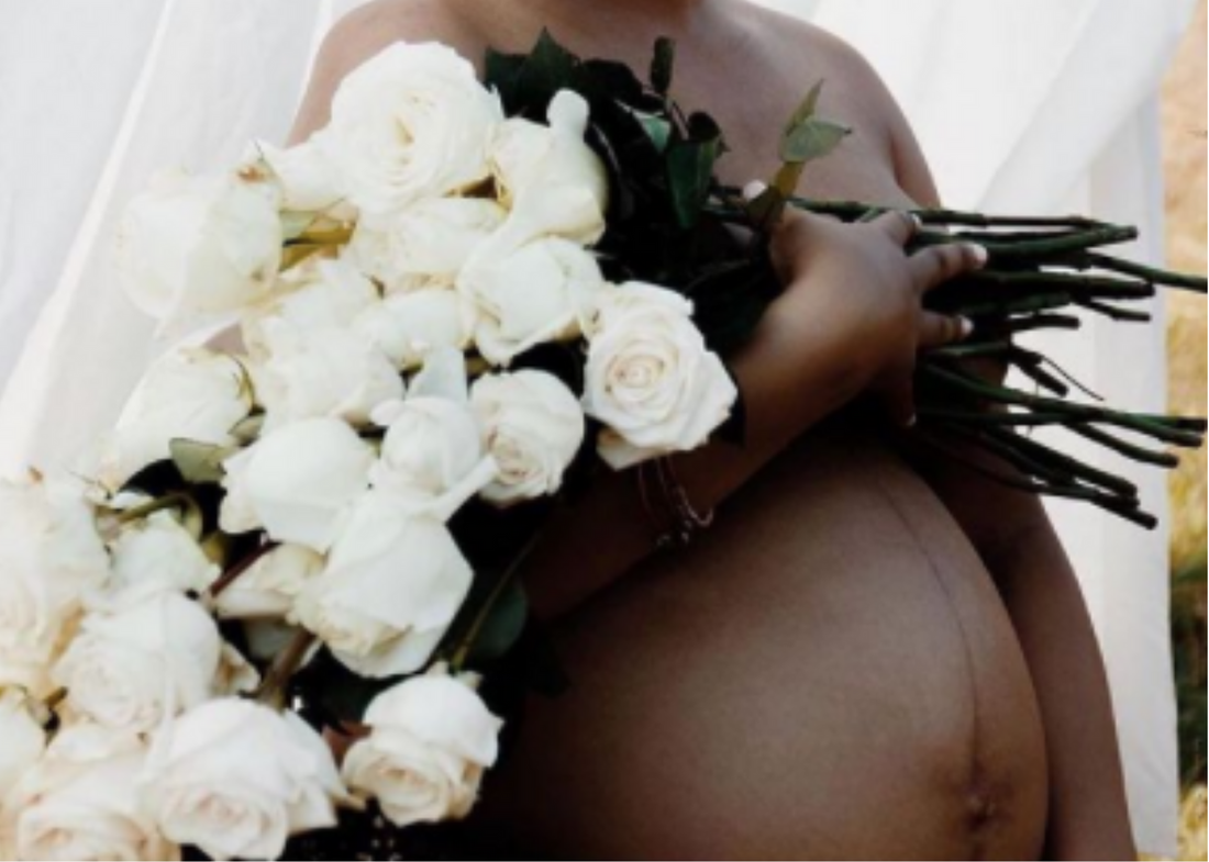 Black Birther Guide to Navigating the Healthcare System - Closeup of Pregnant  Belly Surrounded by White Flowers 