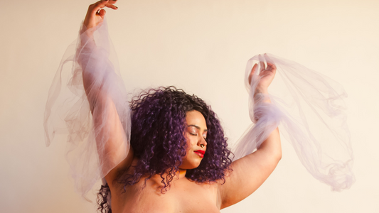 How We're Celebrating Black History Month - Topleess Model Dancing And Holding a Purple Cloth on a Beige Background