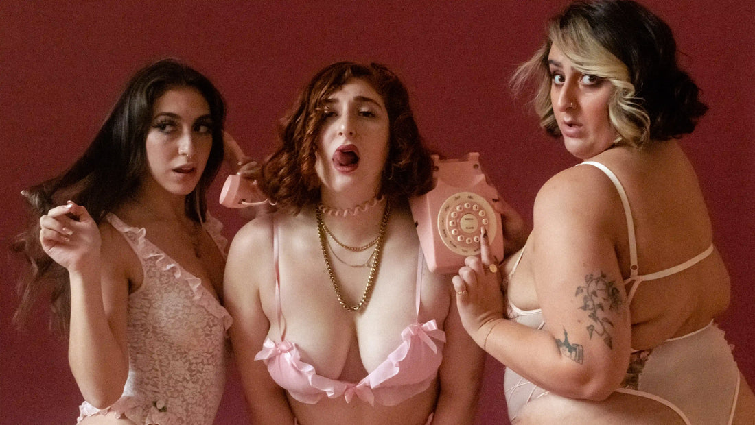 Curious about kink? Three girls sitting in pink lingerie on a retro telephone