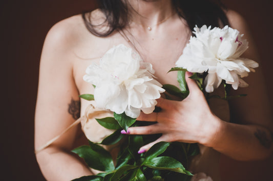 A Commitment to Our Community & Our Planet - Model in Beige Dress Holding White Flowers Close to her Chest