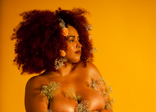 Unpacking the Sexual Wellness Industry's Whitewashing Problem - Topless Black Model Covered in Small Flowers on Yellow Background