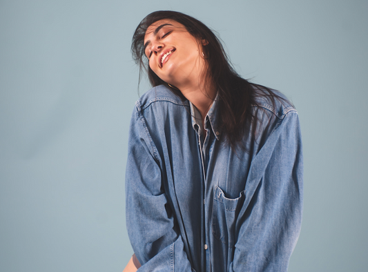 A Guide to Vaginal Probiotics - Model in Denim Shirt Smiling on Blue Background