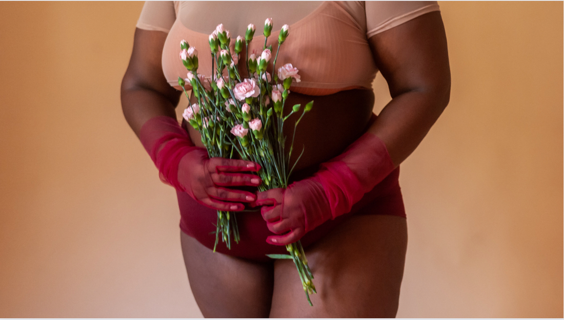 Vaginal infection causes - Torso of model in red gloves holding pink flowers