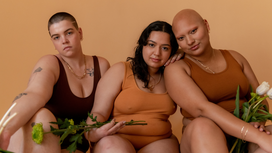 Closeup on three models wearing neutral colored clothing and holding white flowers