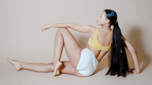 Back of model in yellow bra and white undies posing on the ground 