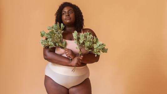 Model wearing light nude undies posing with two branches