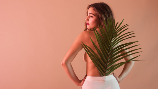 Back of topless model with a large leaf covering back