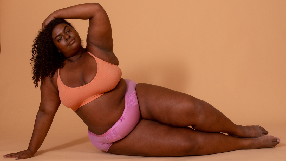  Celebrating Black Health and Wellness - Gabby Fe in orange in pink underwear doing a horizontal pose
