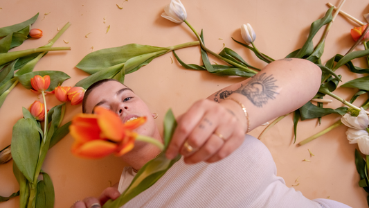 How to prevent vaginal infection and irritation - Model in in white tank top laying down and holding an orange flower