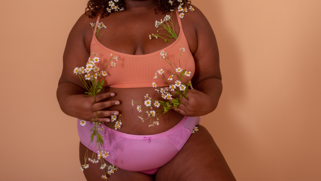 Pelvic Organ Prolapse Pain Point - Model Clutching Flowers Wearing an Orange Bra and Pink Panties