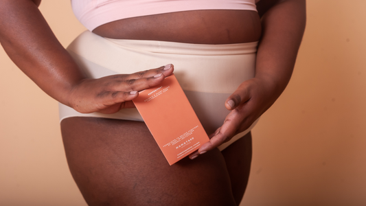 Torso of model holding The Suppository in white panties and light pink bra 