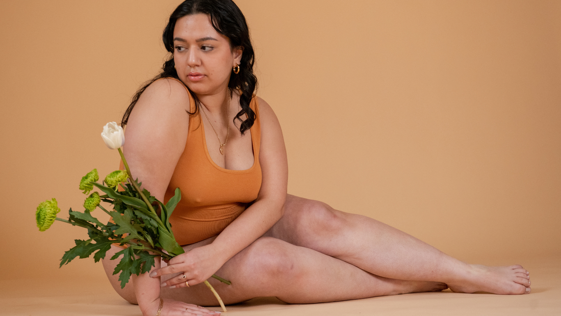 My Herpes Story - Model in orange unitard holding a white rose
