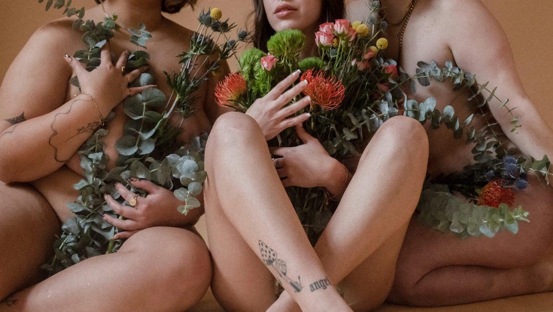 Have you questions about pregnancy, postpartum, and puberty you weren't allowed to ask? Three women hold raw flowers against their nude bodies. 