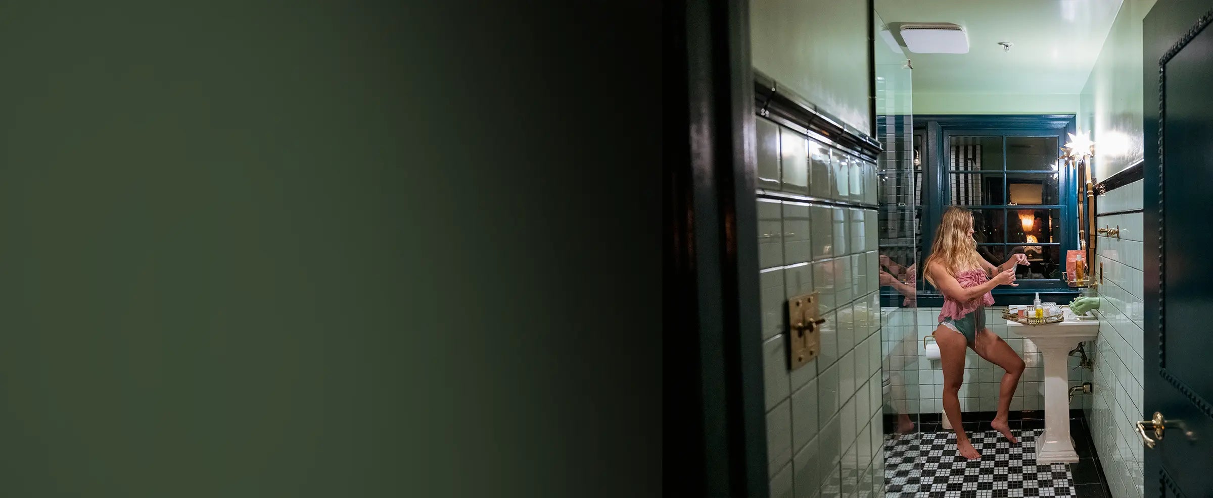 Woman in a bathroom with checkered floor and tiled walls