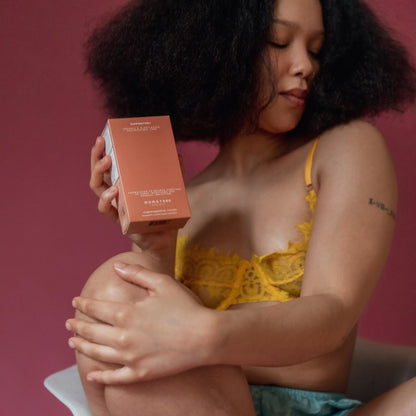 Woman holding a suppository box against a pink background.